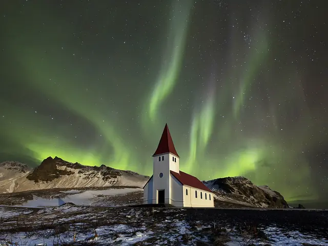 Nordlys over en liten kirke på Island