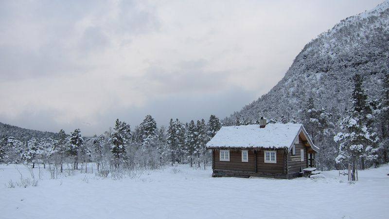 Tradisjonell norsk tømmerhytte i snøen ved Rekdalsetra